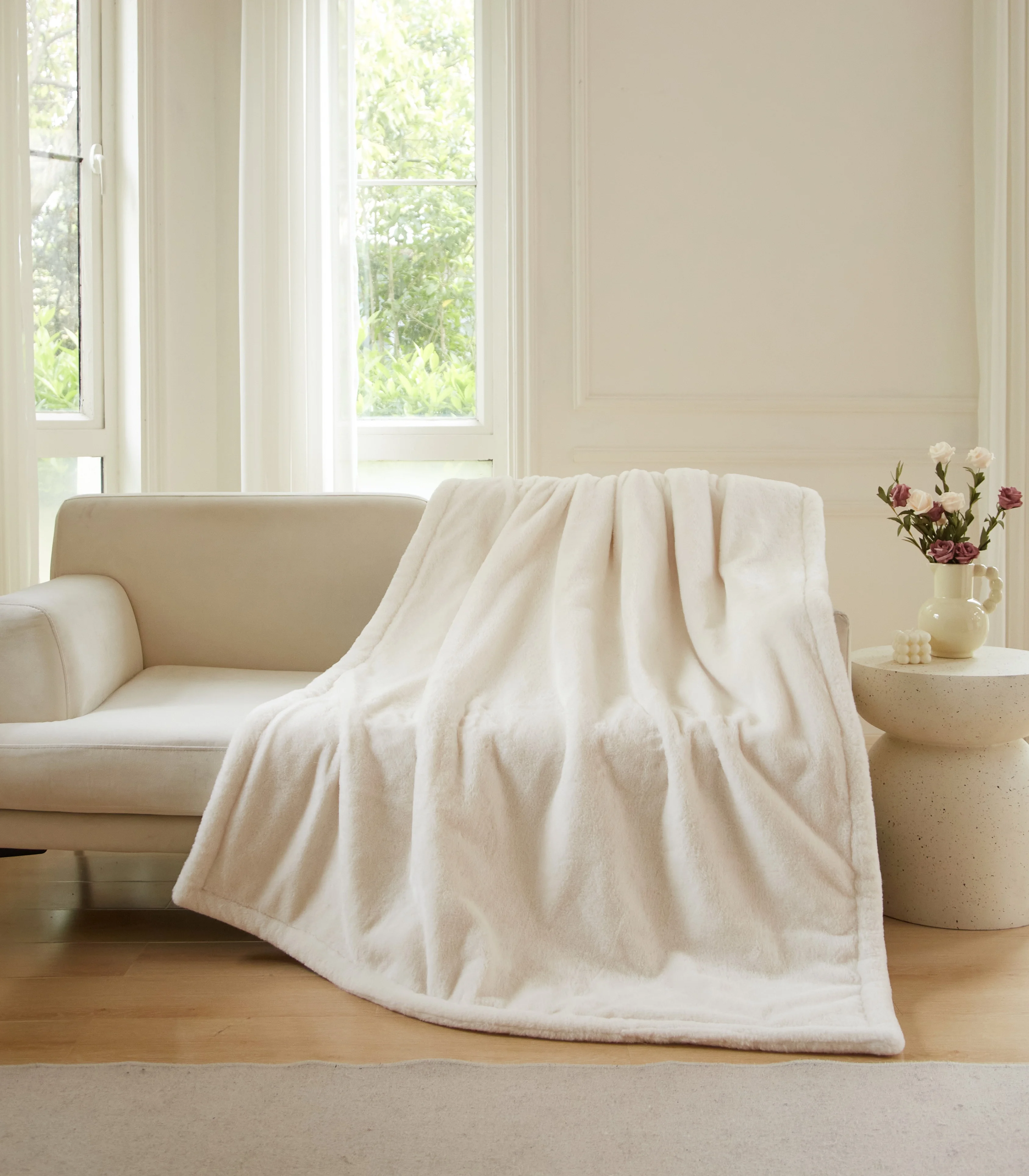 Better Homes & Gardens Vanilla Dream oversized faux fur throw draped over a cream sofa