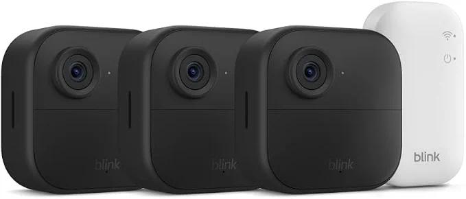 Three black Blink Outdoor 4 wireless security cameras with a white Sync Module Core
